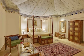 A four-poster bed with a canopy, a wooden cabinet, a mirror, and a traditional rug.