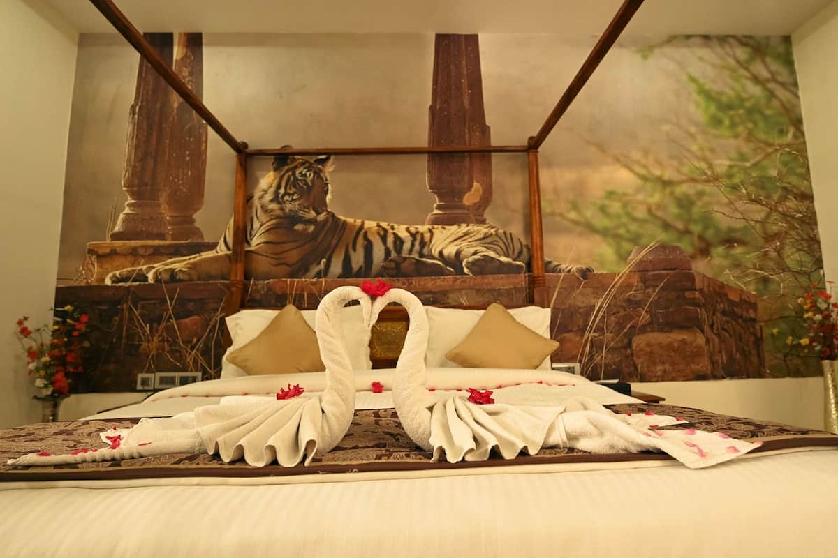 A bed with a tiger mural, a heart-shaped towel arrangement, and a stone wall backdrop.