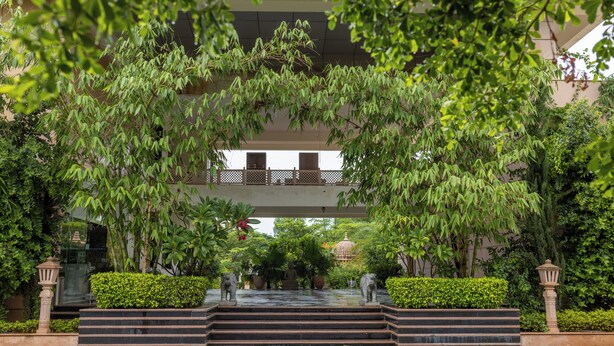 A courtyard with a fountain, steps leading up to a building, and lush greenery. - Tree of Life Tiger Trails, Ranthambore (Sawai Madhopur)