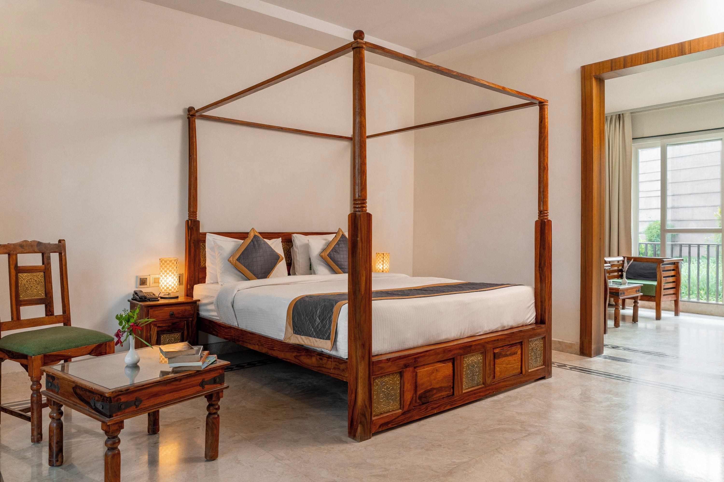 Ein Bett mit Baldachin, dessen Gestell aus Holz besteht, und ein grüner, gepolsterter Sessel.