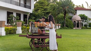 A cart with various food items in front of a building with a balcony and a dome structure in the background.