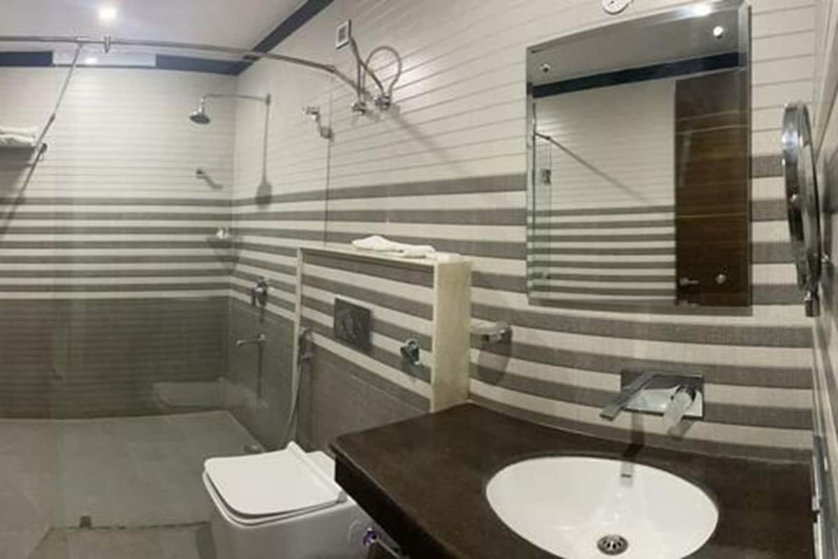 Un baño moderno con ducha de vidrio, inodoro blanco y encimera oscura con lavamanos.