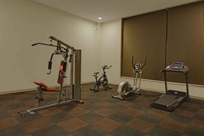 Un gimnasio con cinta de correr, bicicleta estática y máquina de pesas.