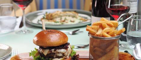 A meal with a burger, fries, and a glass of red wine on a table.