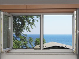 Una ventana con vista al mar y árboles.
