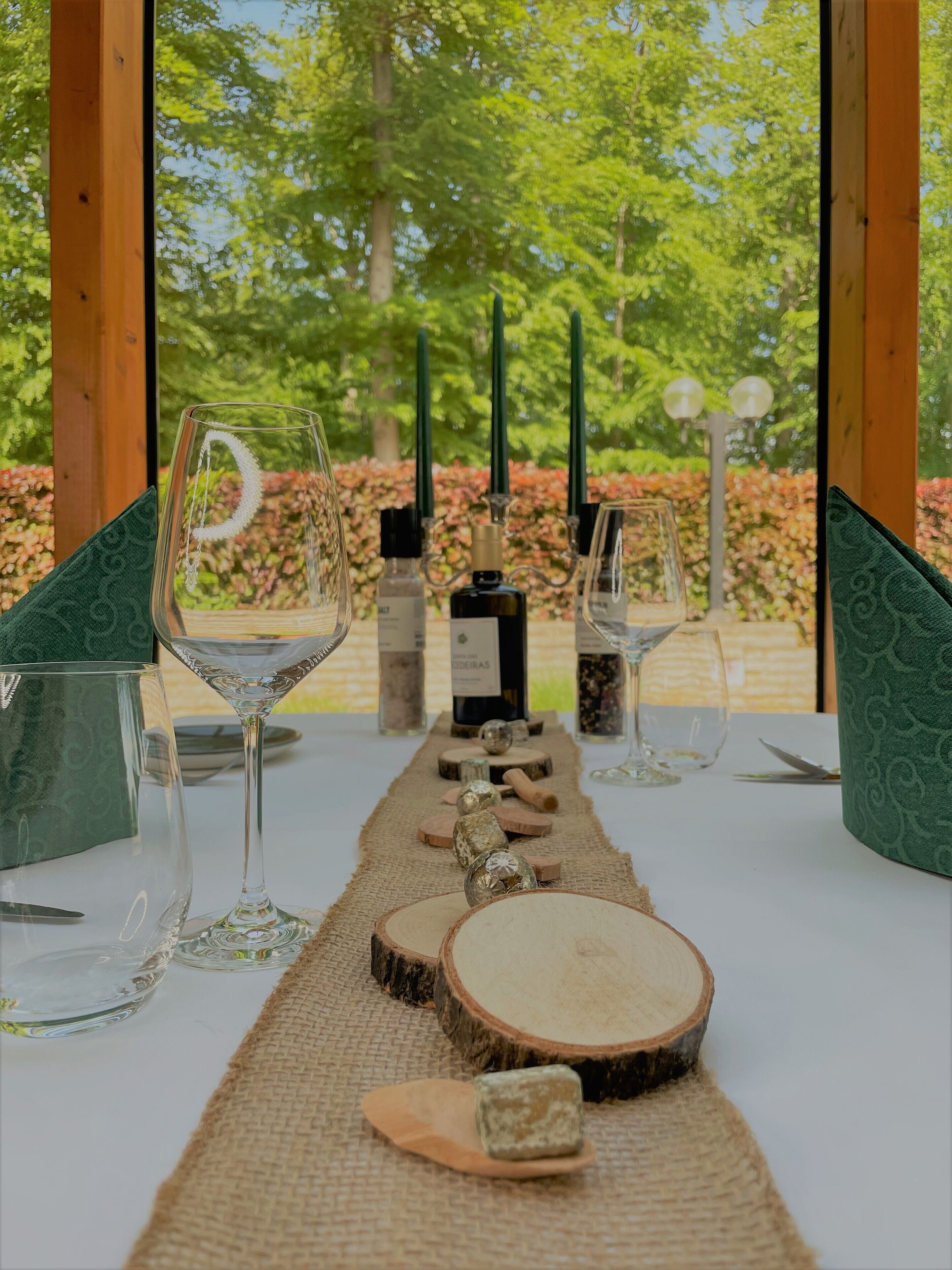 A table set for a meal with wine glasses, bottles, and a rustic centerpiece.