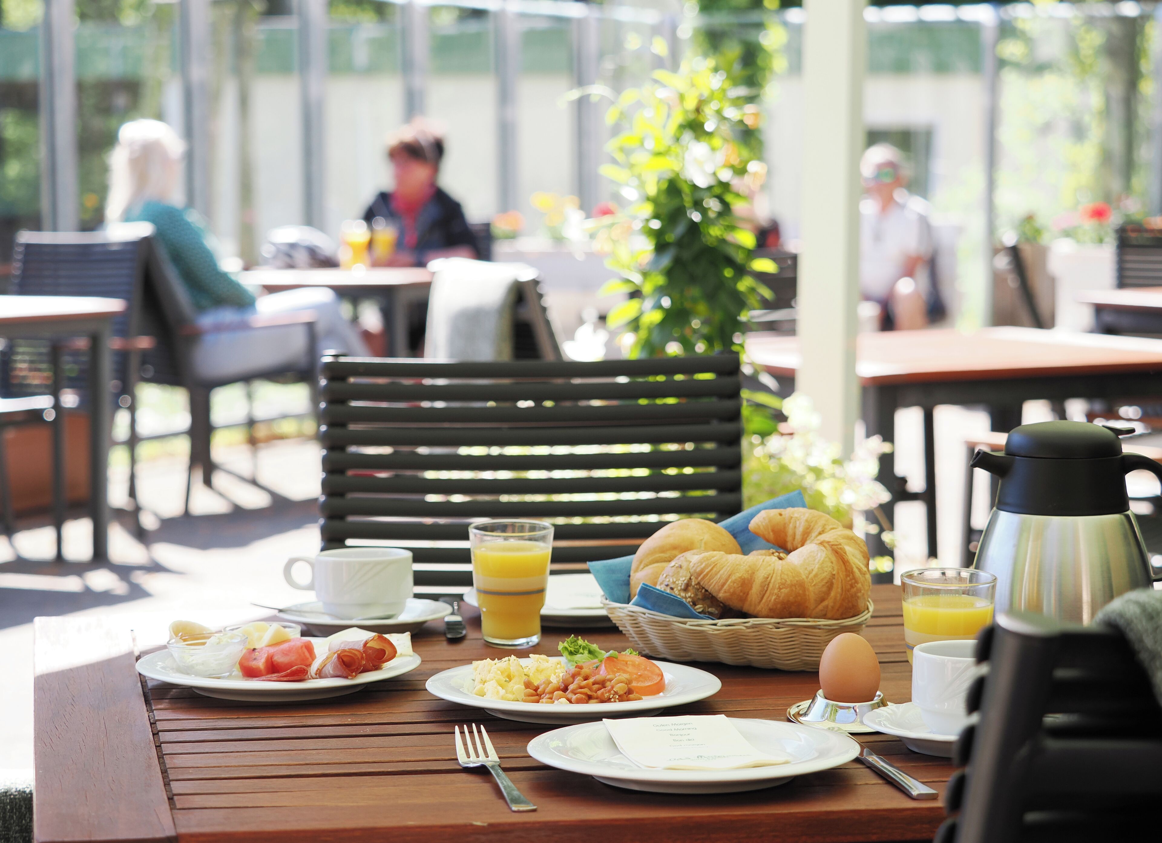 Una mesa de desayuno con croissants, huevos y jugo de naranja.