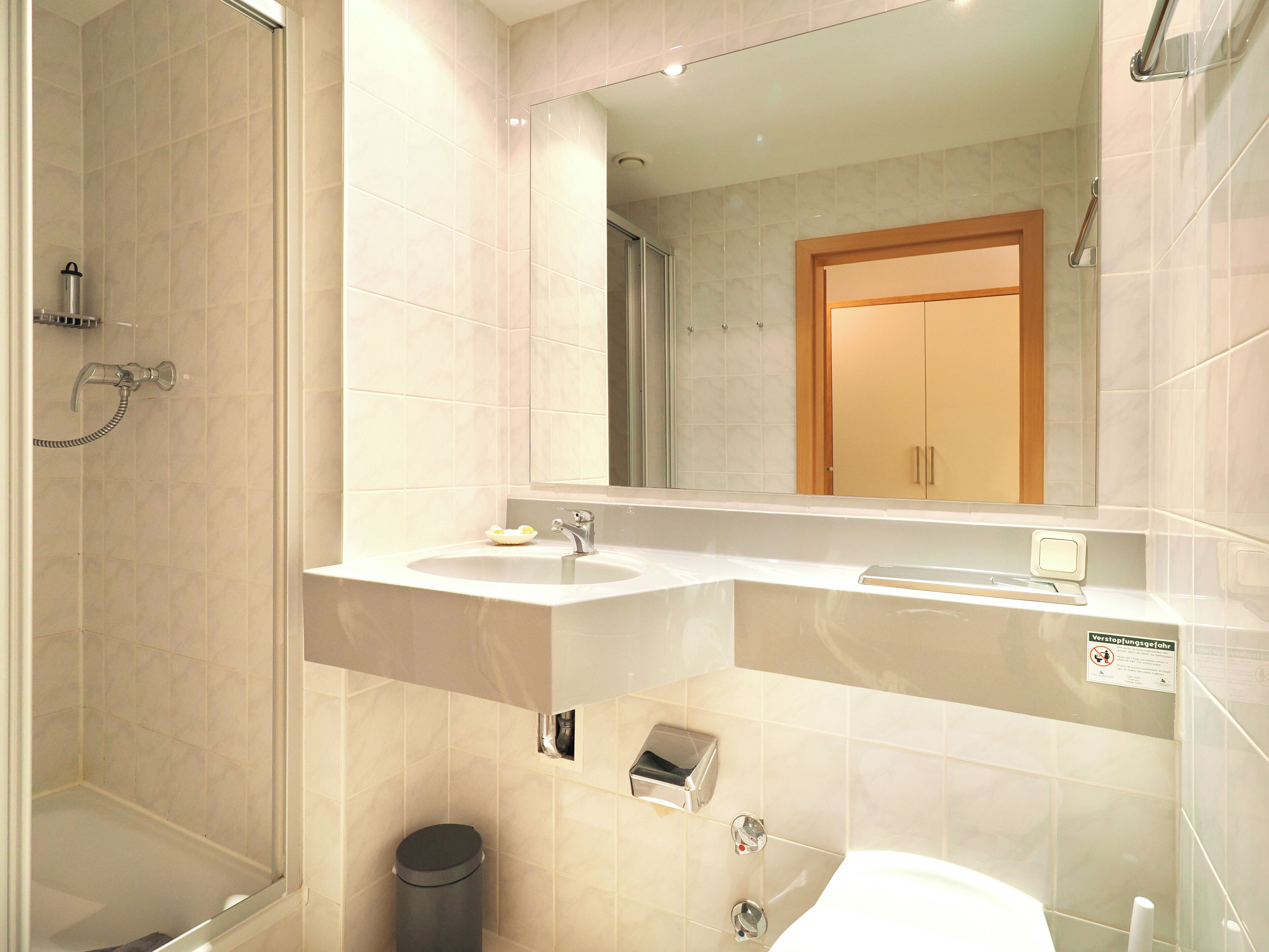 Un baño moderno con cabina de ducha, lavabo e inodoro.