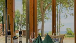 Una mesa cubierta con mantel blanco, servilletas verdes, saleros y pimenteros, copas de vino y cubiertos.