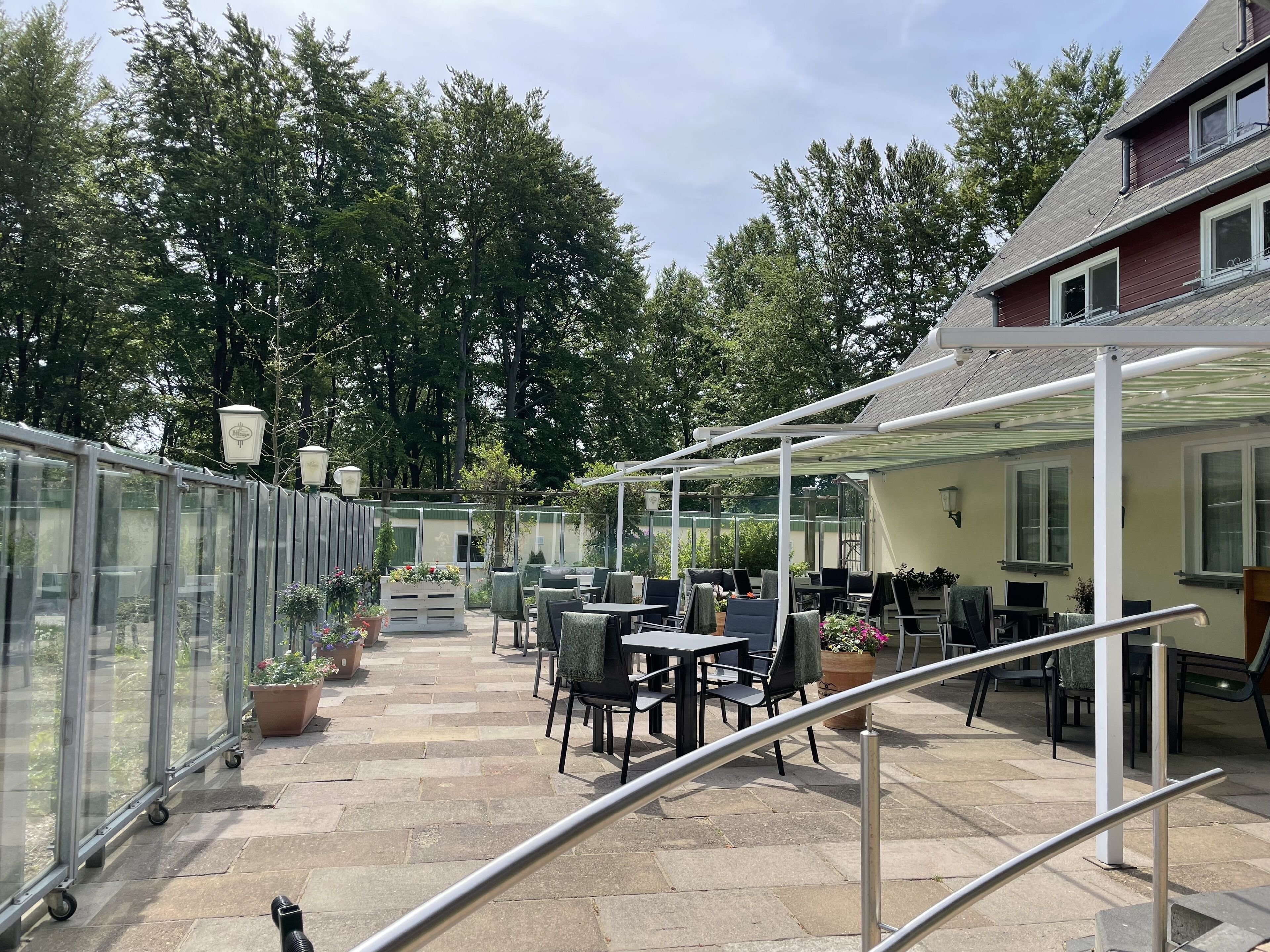 Un espace extérieur aménagé en terrasse, avec des tables et des chaises, une véranda et des plantes en pot.