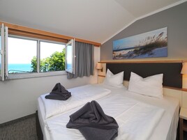 Habitación de hotel con dos camas, un ventanal con vista al mar y un cuadro en la pared.