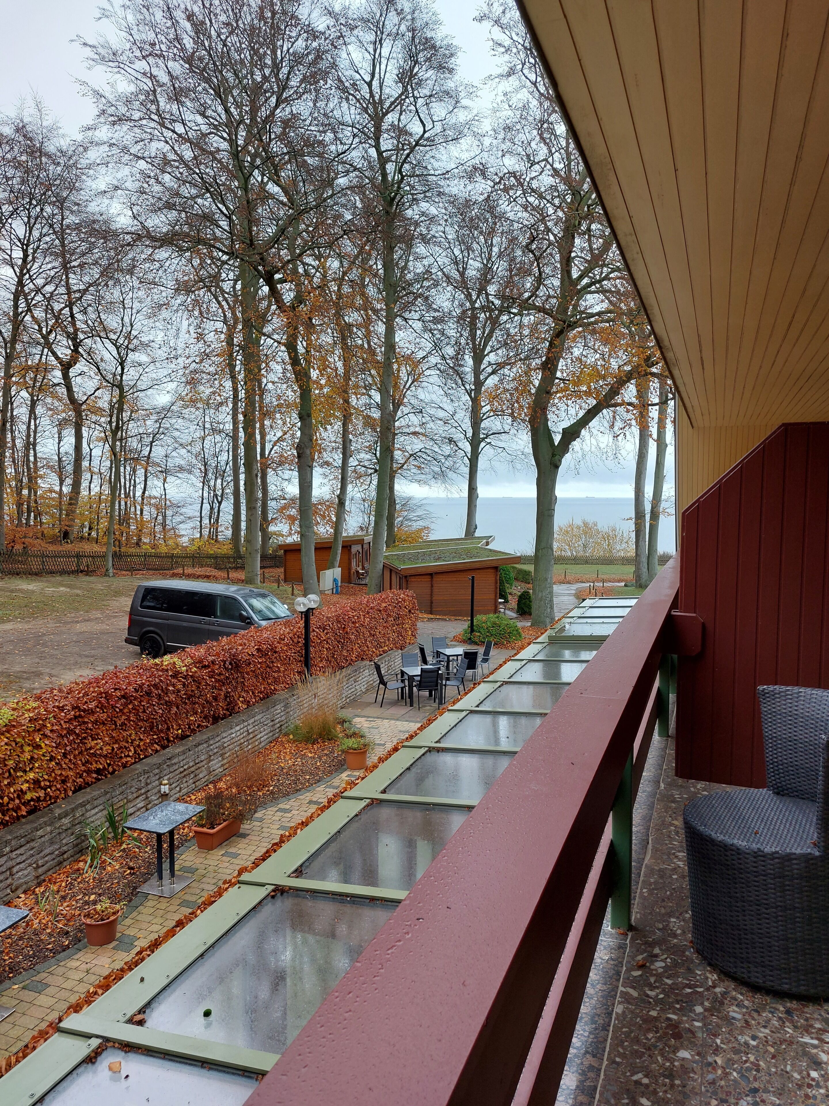 Un espace extérieur abrité, doté d’une terrasse, de sièges et offrant une vue sur des arbres et une étendue d’eau.