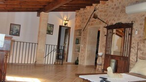 A spacious living area with a wooden table, a patterned rug, and a staircase leading to another room. - Rural estate with pool and professional tennis court (LLucmajor)