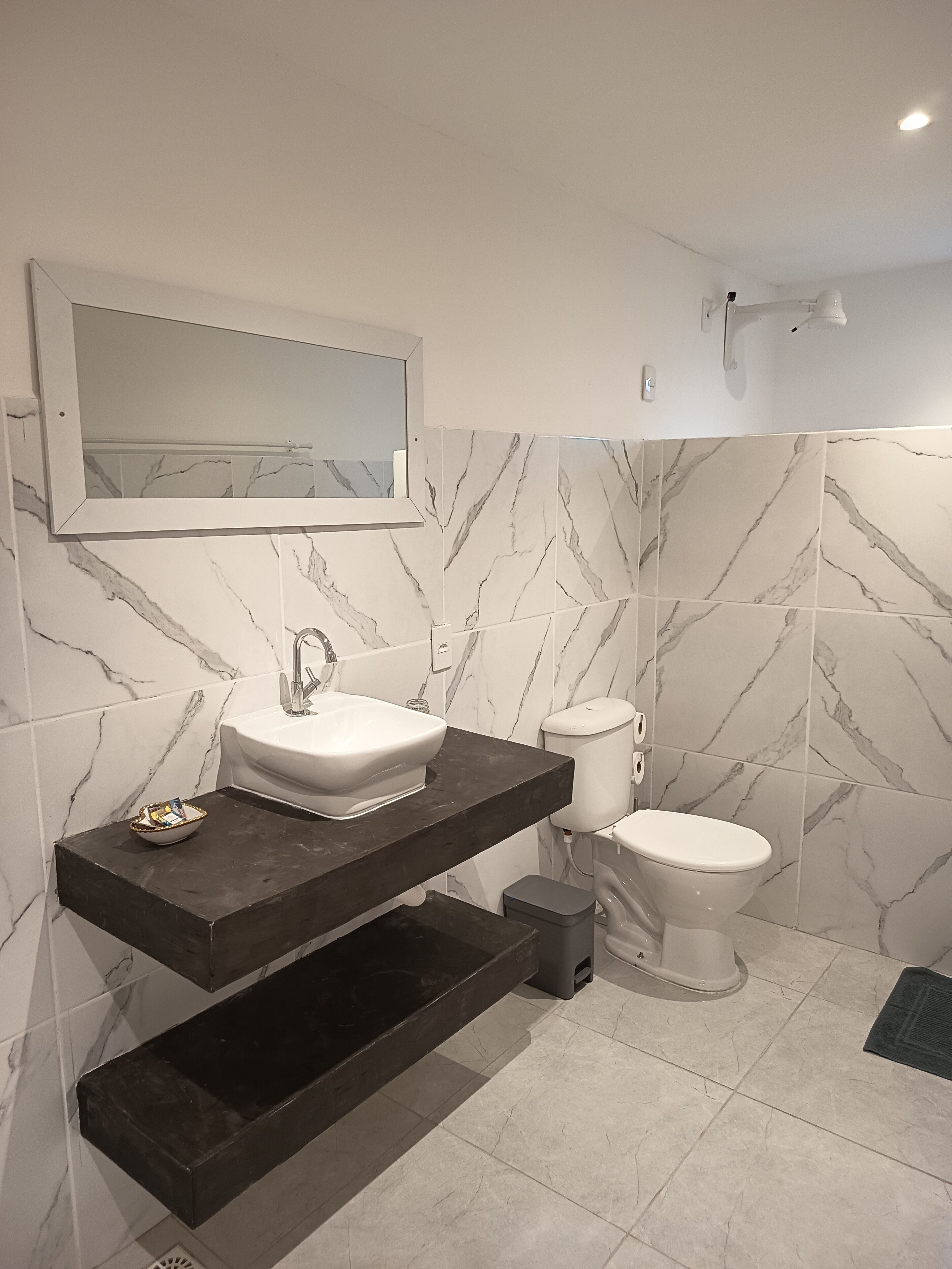 A modern bathroom with a white sink, dark countertop, and marble-patterned walls.
