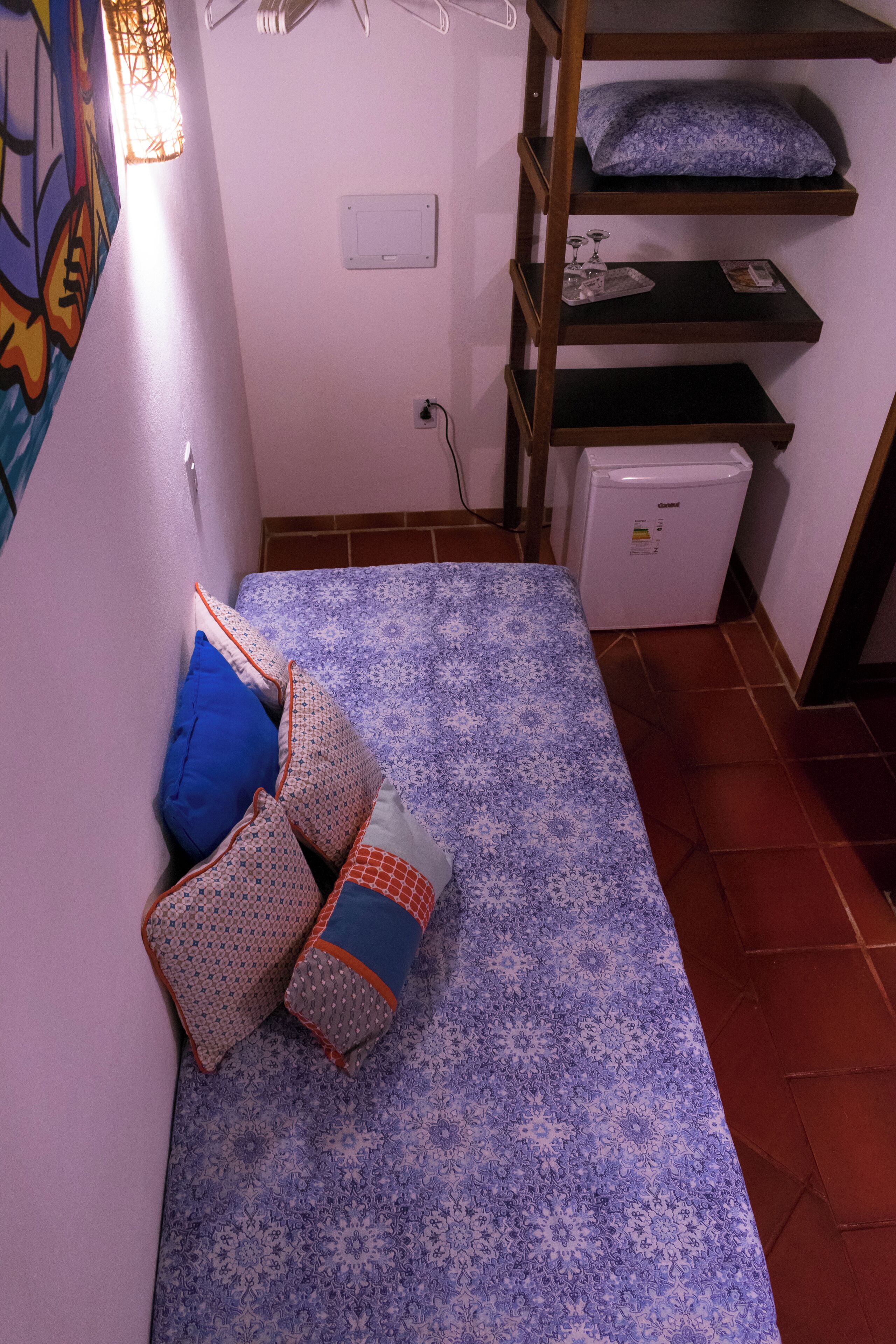 A small room with a bed, a bunk bed, a refrigerator, and a wall with a light switch.