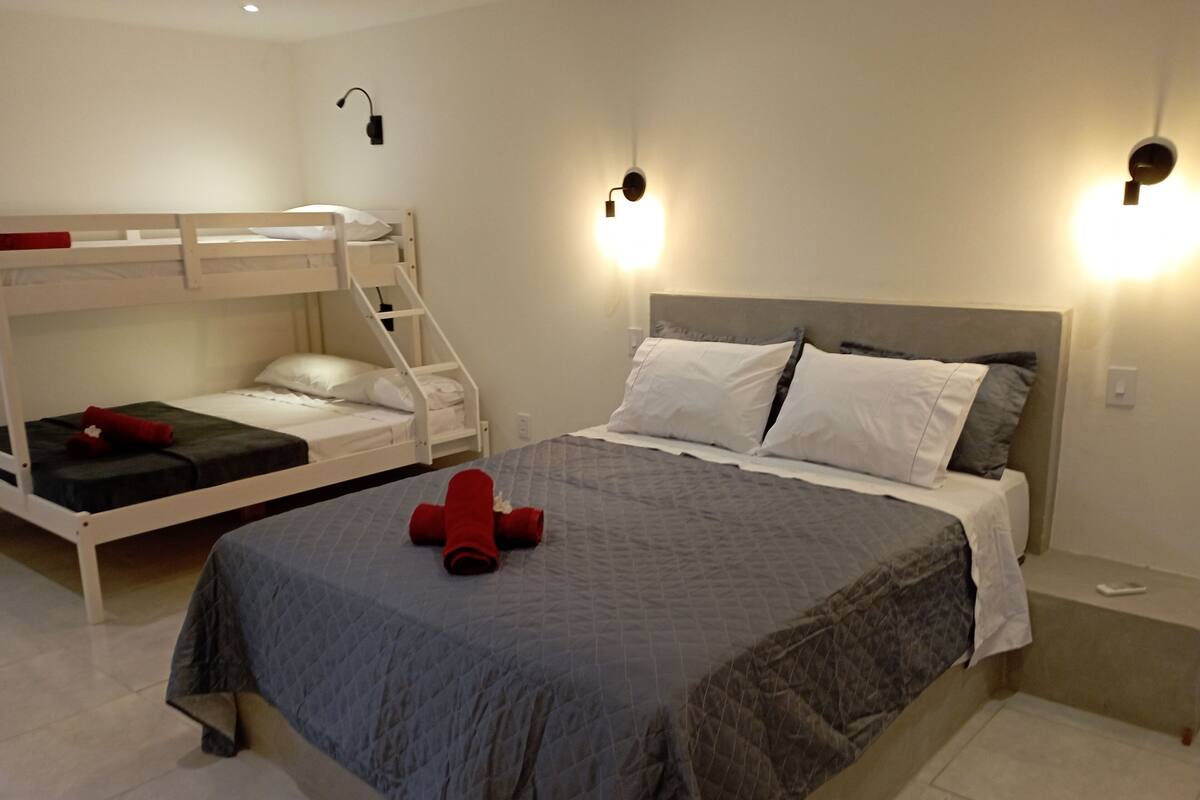 Ein Schlafzimmer mit einem Etagenbett, einem Einzelbett und zwei Wandleuchten.
