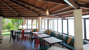 Un espace intérieur aménagé avec des tables et des chaises, un plafond en bois et de grandes fenêtres.