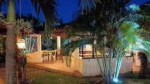 Un espace extérieur bien éclairé, aménagé avec des sièges, des palmiers et un bâtiment à l’architecture moderne.