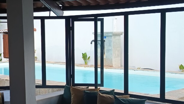 Un espace aménagé avec des sièges, situé au bord de la piscine, d’où l’on peut admirer la piscine et un bâtiment situé au loin.