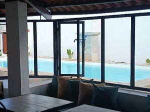 Un espace aménagé avec des sièges, situé au bord de la piscine, d’où l’on peut admirer la piscine et un bâtiment situé au loin.