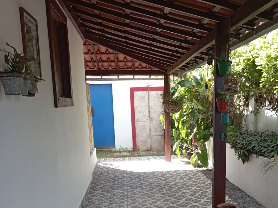 A covered outdoor area with patterned tiles, a blue door, and potted plants.