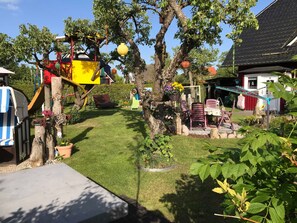 Un jardin bien entretenu, doté d’un espace de jeux, de sièges et d’une grande variété de plantes.