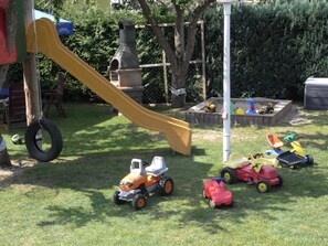 A children's play area with a slide, toy vehicles, and a tire swing. - Haus Schumann - Ostsee - Halbinsel Darss - Ferienwohnung (Wieck a. Darß)