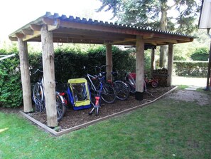 A covered bike parking area with bicycles and a child bike seat.