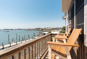 Ein Balkon mit Holzbalkonage, der auf einen Jachthafen mit Booten blickt.