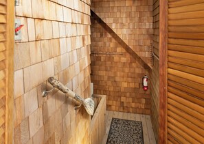 A wooden interior with a wooden staircase, a fire extinguisher on the wall, and a patterned rug on the floor.