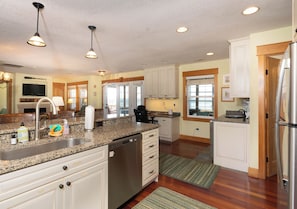 A kitchen with white cabinets, a granite countertop, stainless steel appliances, and pendant lighting.