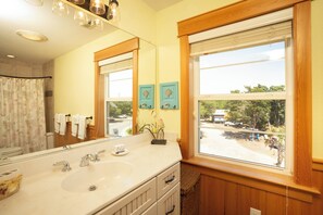 Ein Badezimmer mit einem großen Spiegel, einem Waschbecken und einem Fenster mit Blick nach draußen.