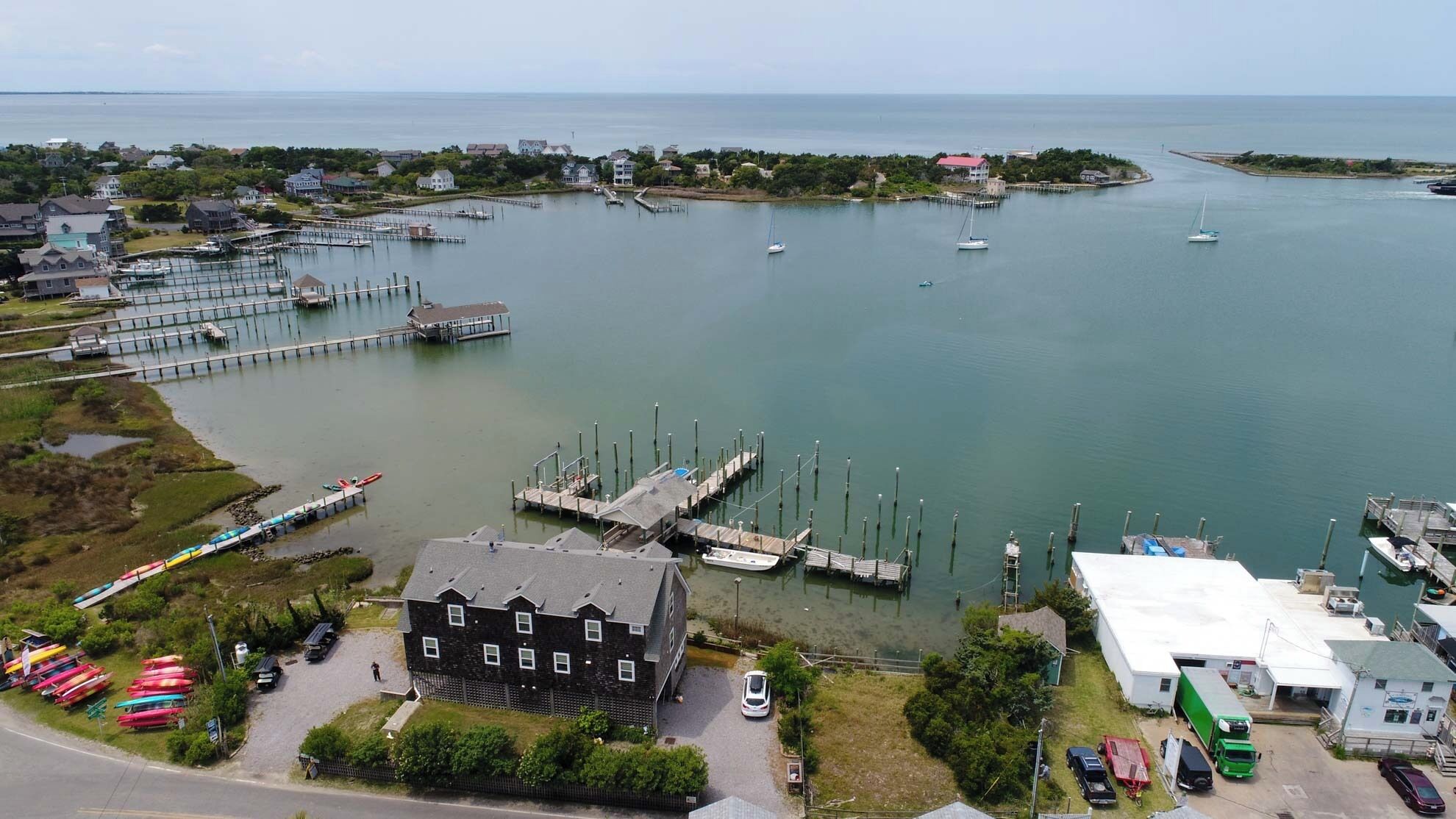A marina with docks and boats, surrounded by residential buildings and a large house with a driveway.