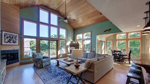A spacious living room with a fireplace, large windows, and a dining area.