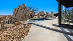 A modern outdoor pool area with a view of rocky terrain and a clear blue sky. - Black Desert House ft in Architectural Digest (Yucca Valley)