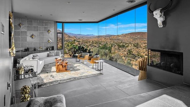 A modern living room with a large window, a fireplace, and a bull skull decoration. - Black Desert House ft in Architectural Digest (Yucca Valley)