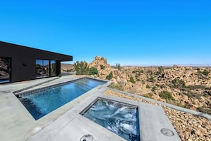 A modern pool area with two separate pools, one rectangular and one square, surrounded by a rocky landscape. - Black Desert House ft in Architectural Digest (Yucca Valley)