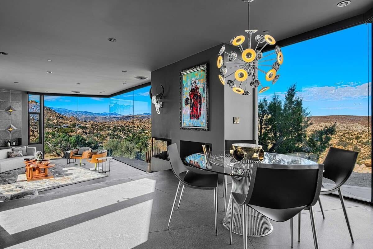 A modern interior with a dining area, large windows, and a view of the landscape.