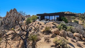 A modern building with a flat roof, large windows, and a patio area. - Black Desert House ft in Architectural Digest (Yucca Valley)