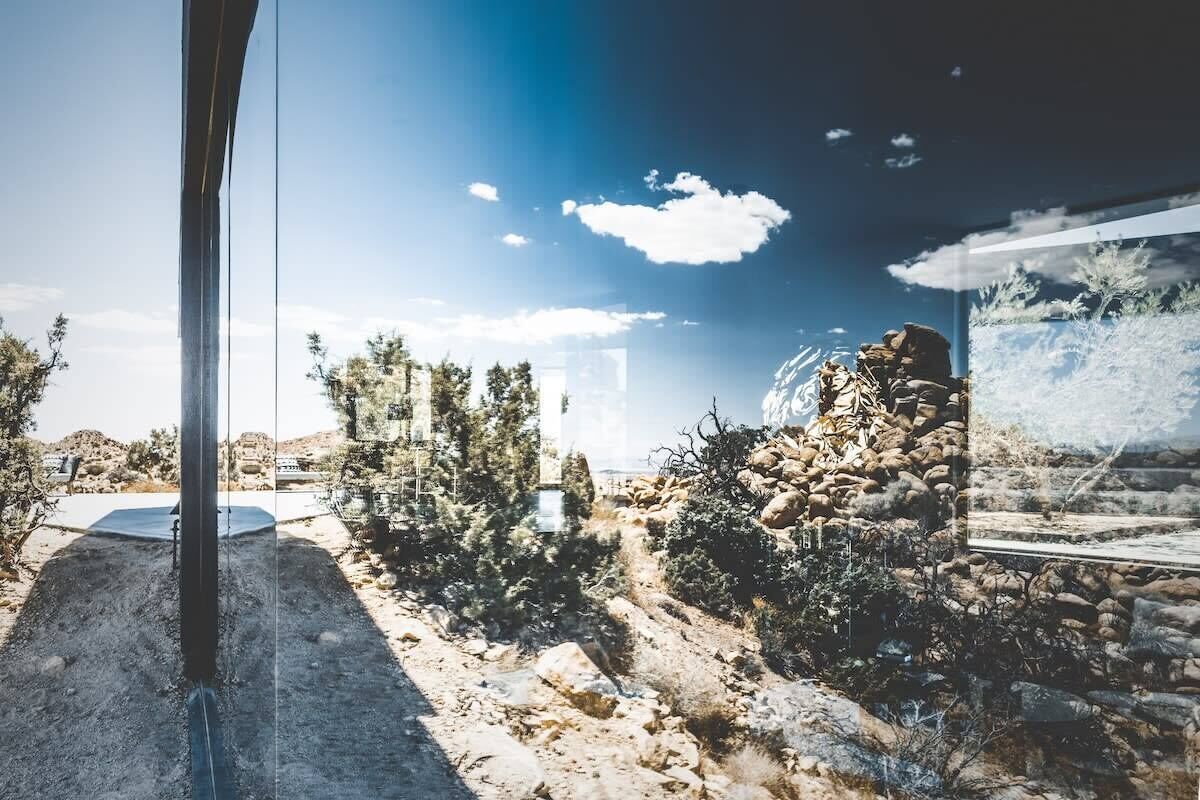 A desert landscape with a stone wall, sparse vegetation, and a clear sky.