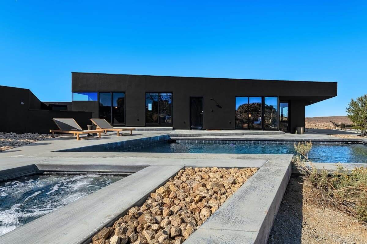 A modern building with a pool, lounge chairs, and a clear sky.