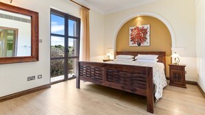 Un dormitorio con una cama grande, una ventana, un cuadro y una mesita de noche.