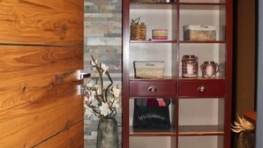 Ein Holzschrank mit Glaseinsatz, ein gewebter Korb als Ablage und eine Vase mit Zweigen.
