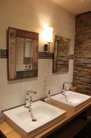A bathroom with two sinks, a mirror, and a wall-mounted light. - Ferienwohnung Panorama Postwiese (Winterberg)