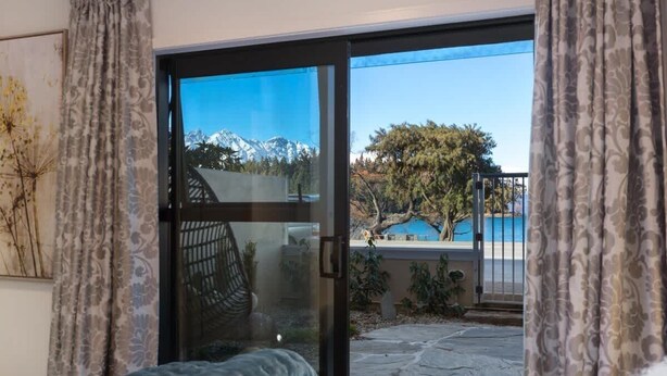 A bedroom with a large sliding glass door leading to a balcony with a view of a mountain and a pool.