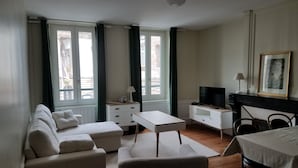 Quarto de hotel moderno com sofá, uma mesinha, televisão e lareira.