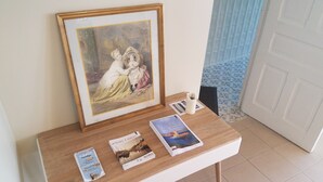 Uma mesa com um quadro emoldurado, vários livros e um vaso branco.