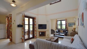 Una sala de estar con sofá, mesa de centro, televisor, chimenea y un comedor con sillas y una mesa.