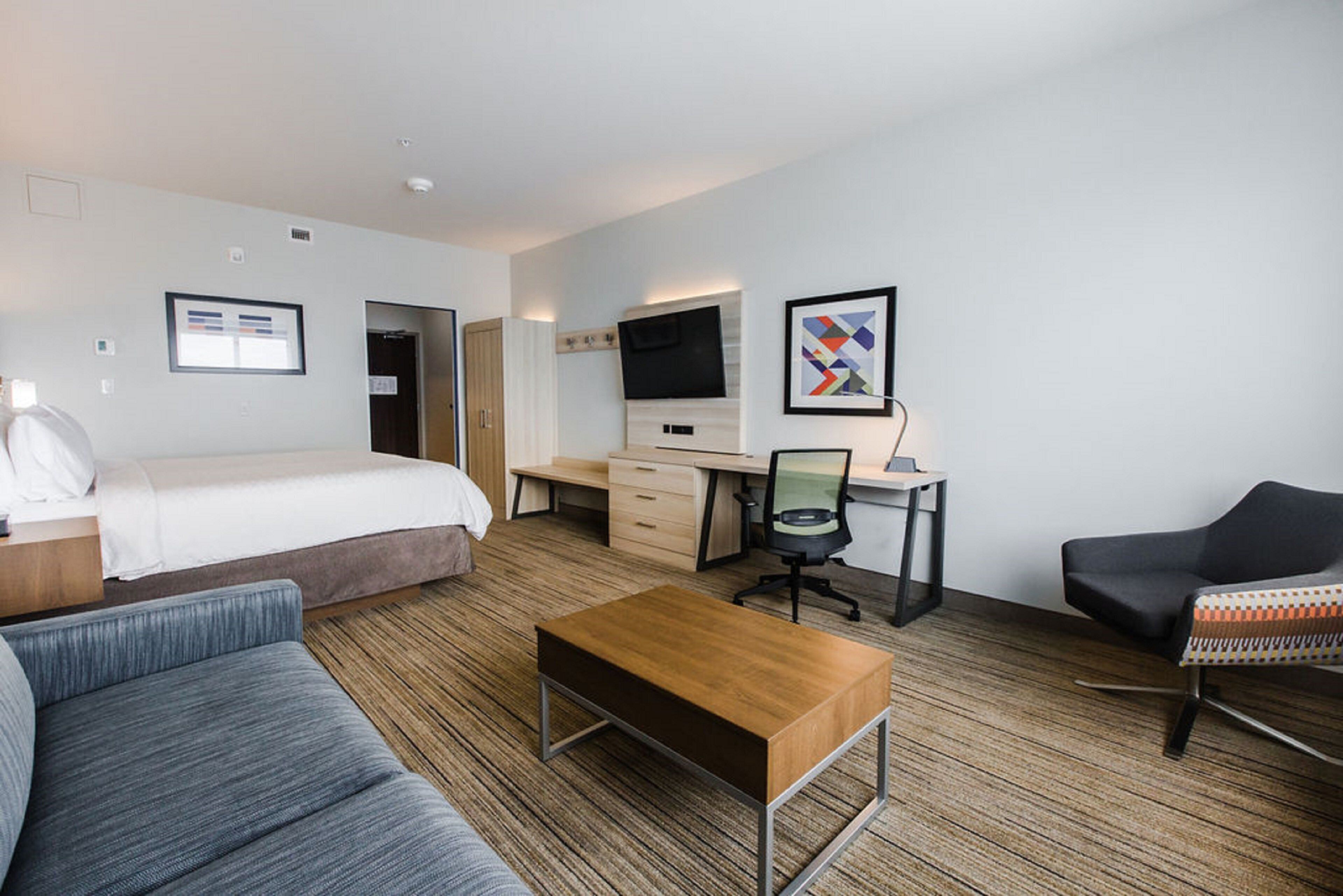 Una habitación de hotel con una cama, un escritorio, una computadora, una silla y un sofá.