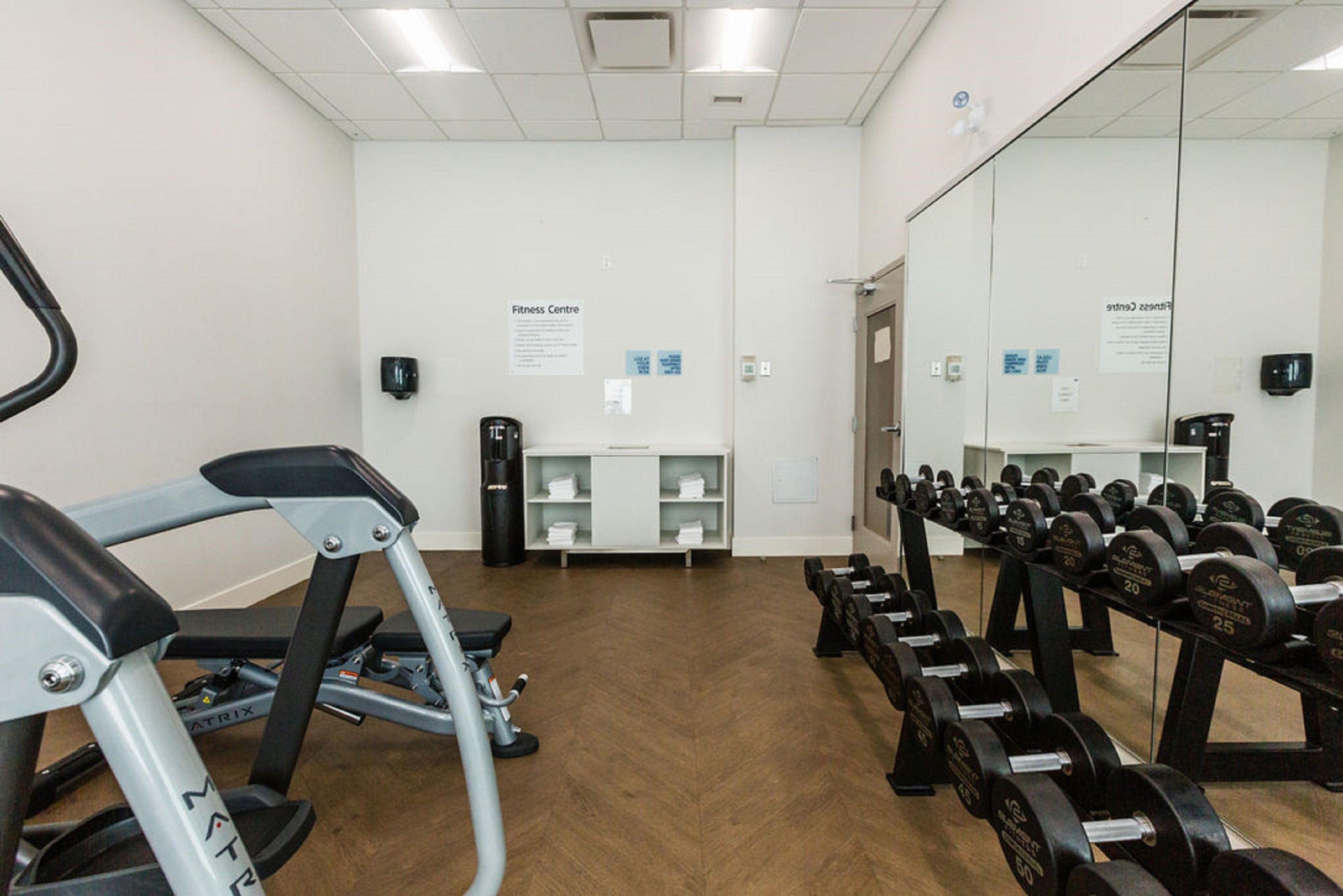 A gym with exercise equipment, a mirror, and a wall-mounted sign.
